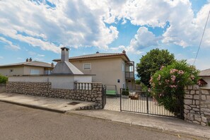 Ein zweistöckiges Haus mit Steinmauer und Metalltor.