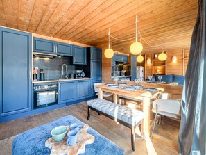 A modern kitchen with blue cabinets, a wooden dining table, and pendant lights. - Comfortable apartment for 6 in central Val-d'Isère with Wifi (Val-d'Isère)