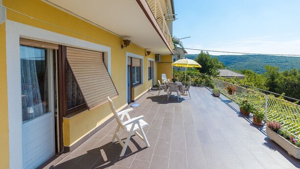 A balcony with a table and chairs, a yellow building, and a view of the landscape. - Dog-friendly apartment with private parking, BBQ area and large balcony (Grižane)