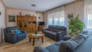 A living room with two sofas, a coffee table, and a TV. There is a wooden cabinet and a plant. - Dog-friendly apartment with private parking, BBQ area and large balcony (Grižane)