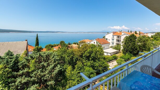 Un balcon donnant sur une ville côtière, avec vue sur les bâtiments et les arbres.