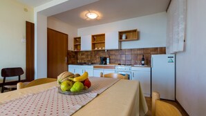 Une petite cuisine équipée d’une table à manger pour deux personnes, d’un réfrigérateur et d’une cuisinière.