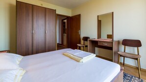 Une chambre à coucher comprenant un lit, un bureau, une chaise, une armoire et un miroir.