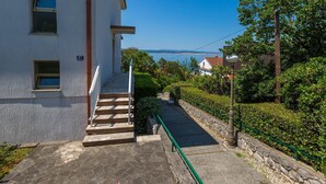 Un escalier menant à un bâtiment, avec un chemin de pierre et de la verdure.
