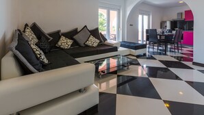 Una sala de estar moderna con un sofá y un sillón, una mesa de centro de vidrio y un piso a cuadros.