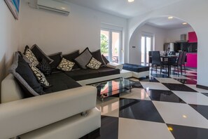 Ein modernes Wohnzimmer mit einer Couch und einem Sessel, einem Glastisch und einem Schachbrettmuster-Boden.