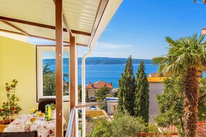 Un balcón con vista al mar, una mesa con alimentos para el desayuno y una planta en maceta.