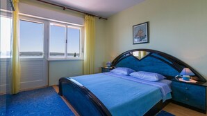 Un dormitorio con cama, mesita de noche, lámpara y ventana con cortinas.
