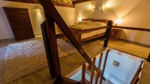 Ein Schlafzimmer mit einem hölzernen Bett, einer Steinwand und einer Treppe.