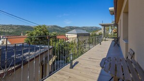 Ein Balkon mit Holzboden, Metallgeländer und Blick auf einen Berg.