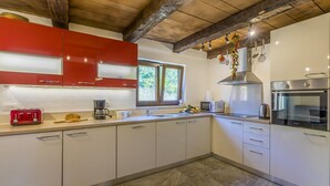 Eine moderne Küche mit weißen Schränken, einem roten Gerät und einem Fenster, das natürliches Licht hereinlässt.