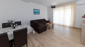 A modern living room with a sofa, a dining table with chairs, and a small coffee table. - Impressive apartment just 400 metres from the sandy beach with panoramic views (Crikvenica)