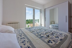 A bedroom with a large bed, a mirrored wardrobe, and a sliding glass door leading to a balcony. - Cosy apartment just 250 metres from the beach with sea view, private parking, WiFi (Dramalj)