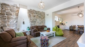A living room with a stone wall, a sofa, a coffee table, and a bean bag. - Unique villa with private pool, sea view, trampoline, bikes and many hiking trails in the area (Jadranovo)