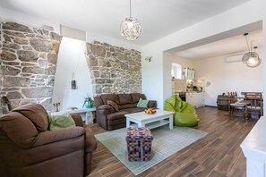 A living room with a stone wall, a sofa, a coffee table, and a bean bag. - Unique villa with private pool, sea view, trampoline, bikes and many hiking trails in the area (Jadranovo)