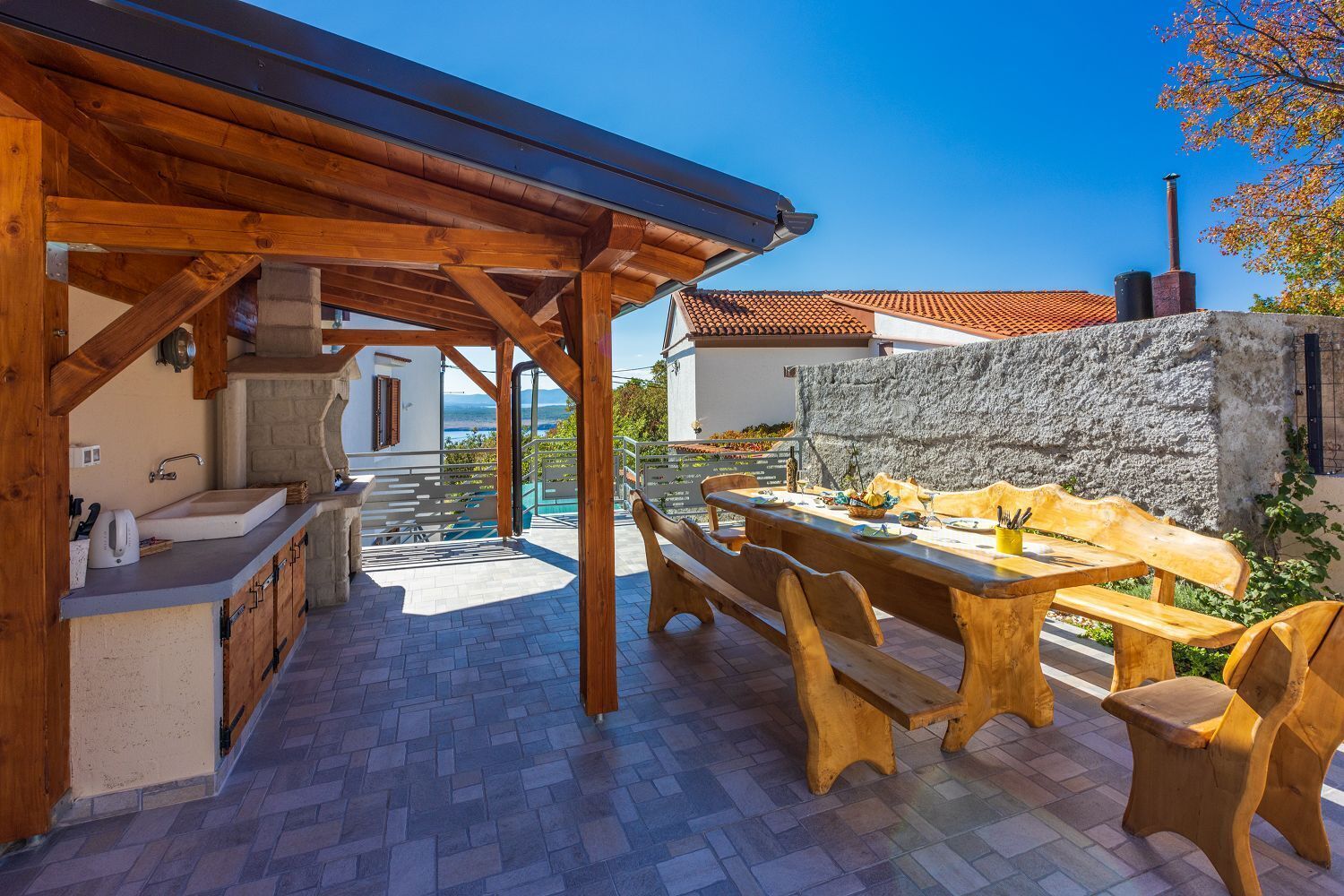 Un'area pranzo all'aperto coperta, con mobili in legno e una parete in pietra.