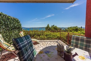 Un balcone con vista sul mare, arredato con due sedie e un tavolo.