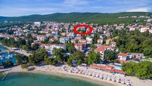 Luftaufnahme einer Küstenstadt mit Strand, Wohnhäusern und einem Yachthafen.