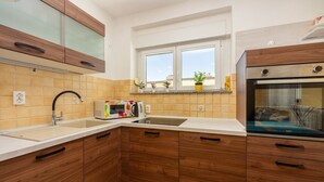 Eine Küche mit Holzausstattung, einer Mikrowelle, einem Wasserkocher und einem Fenster mit Pflanzen.