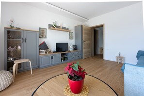 A modern living room with grey cabinets, a TV, and a red potted plant. - Unique apartment just 200 metres from the sandy beach with sea view, parking space, sun loungers, air conditioning (Crikvenica)
