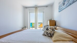 Een slaapkamer met een bed, kussens, een houten hoofdbord, een nachtkastje, een kast en een schilderij aan de muur.