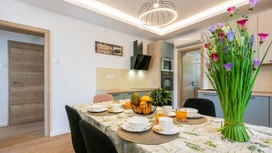 Een ontbijtruimte met een tafel gedekt, inclusief fruit, een ananas, en een bloevas.