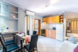 Eine moderne Küche mit Holzausstattung, einem Essbereich mit Tisch und Stühlen sowie einem sichtbaren Backofen und einer Mikrowelle.