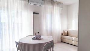 A dining area with a round table, chairs, and a white air conditioning unit above. - Studio Apartment Near Piazza Nember (Jesolo)
