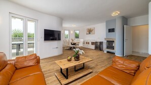 Een moderne woonkamer met leren banken, een houten salontafel en een aan de muur bevestigde televisie.