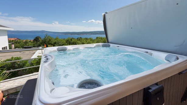 Een bubbelbad met vrij uitzicht op zee en bergen op de achtergrond.