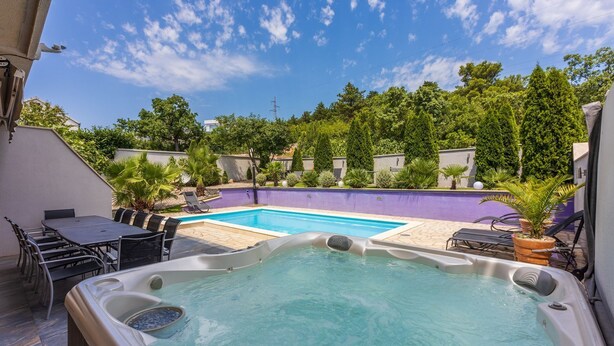 Ein Whirlpool mit Pool, Sitzgelegenheiten im Freien und üppiger Bepflanzung.