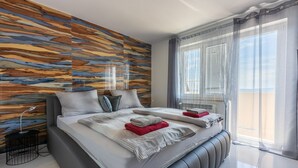 Ein modernes Schlafzimmer mit einem großen Bett, einer Holzverkleidung und Blick auf den Himmel durch das Fenster.