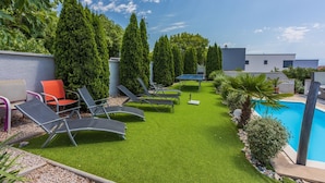 Ein Poolbereich mit Kunstrasen, Liegestühlen und einem Tischtennis-Tisch.