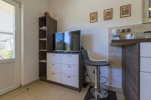 A compact living space with a TV on a wooden cabinet, a small bar stool, and a kitchen area with a coffee maker. - Fantastic apartment just 400 metres from the beach with private parking and washing machine (Dramalj)