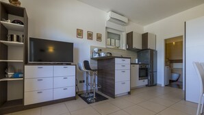 Eine moderne Küche mit weißen Schränken, einem eingebauten Backofen und einem großen Flachbildfernseher.