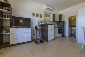 A modern kitchen with white cabinets, a built-in oven, and a large flat-screen TV. - Fantastic apartment just 400 metres from the beach with private parking and washing machine (Dramalj)