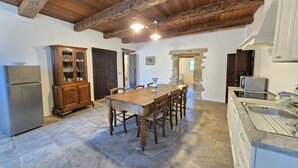 Une cuisine rustique avec une table en bois, un sol en pierre et des poutres apparentes.