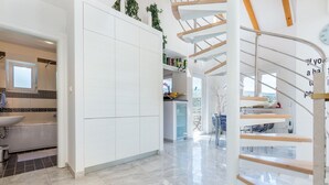 Eine moderne Küche mit weißen Schränken, einer eingebauten Spüle und einer Wendeltreppe.