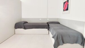 A minimalist room with two single beds, a white wall, and a framed abstract artwork. - Comfortable Studio Near Piazza Nember (Jesolo)