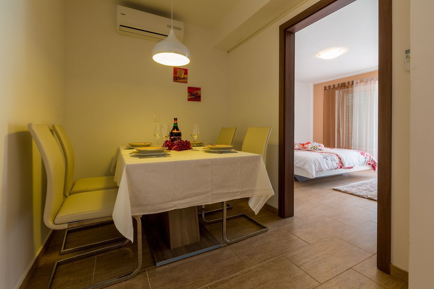 Ein Essbereich mit einem für zwei gedeckten Tisch, einer Champagnerflasche und zwei Gläsern. Im Hintergrund ist ein Bett zu sehen.