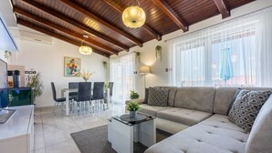 A modern living room with a sofa, coffee table, and dining area.