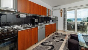 Una cucina moderna con mobili in legno, elettrodomestici in acciaio inossidabile e vista all'esterno tramite una porta scorrevole in vetro.