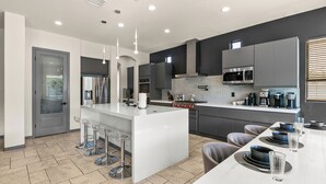 Een moderne keuken met een centraal eiland, barstoelen en een eettafel voor vier personen.