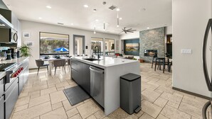 Een moderne keuken met een centraal eiland, roestvrijstalen apparatuur en een eetgedeelte met uitzicht.