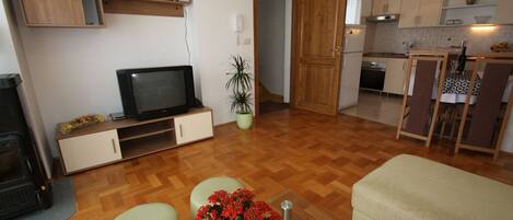 A compact living space with a TV, kitchenette, and seating area.