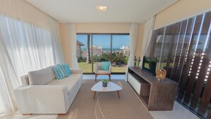 A modern living room with a sofa, armchair, coffee table, and a TV on a wooden console. - Villa Sumatera Beach (Trairi)