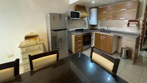 A kitchen with a refrigerator, microwave, stove, and wooden cabinets.