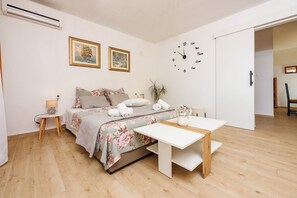 Ein modernes Schlafzimmer mit einem Bett, Nachttisch, einer Uhr und einem kleinen Tisch mit einer Vase.