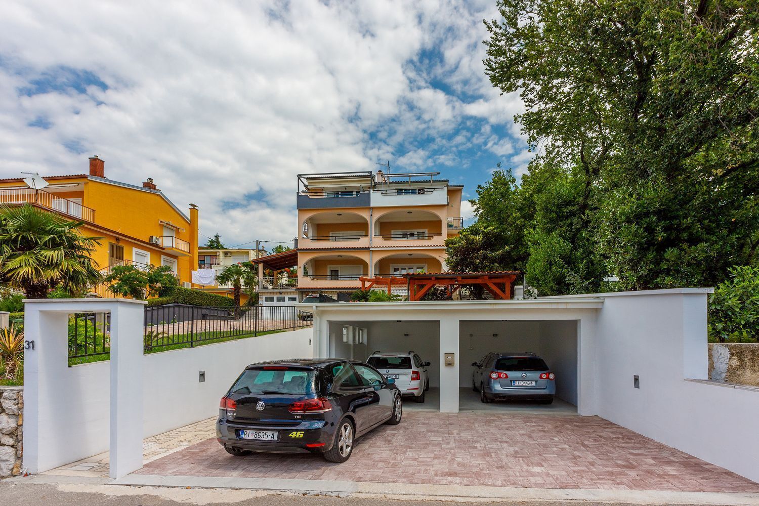 A multi-story residential building with a covered parking area.