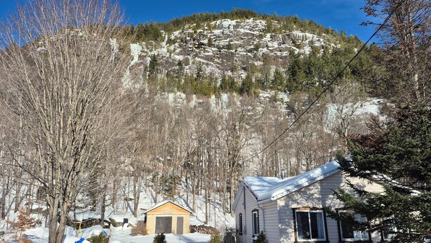 Paisaje nevado con una casa y un cobertizo pequeño.